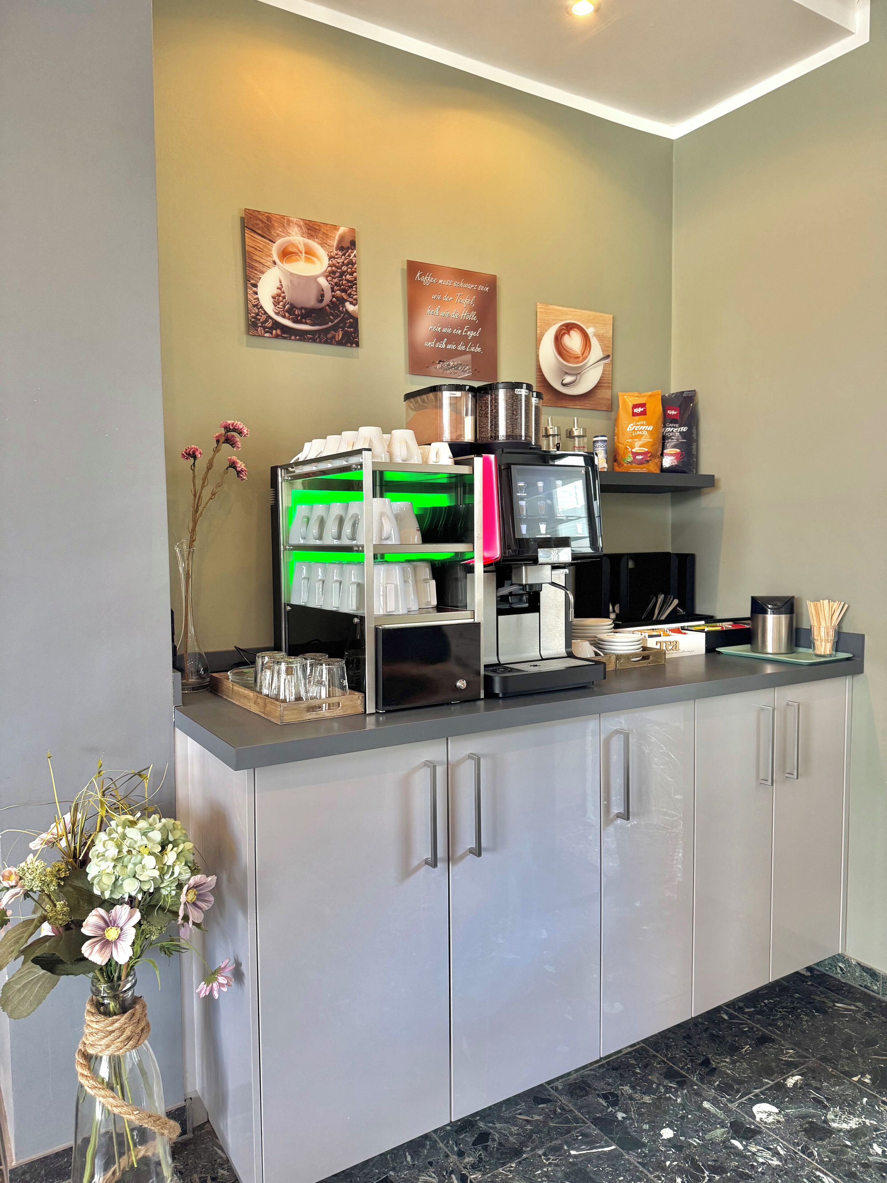 Un comptoir de café avec une machine à café, des tasses et un présentoir de grains de café.