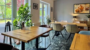 Uma sala de jantar com uma mesa de madeira, cadeiras e uma janela grande com vista para árvores.
