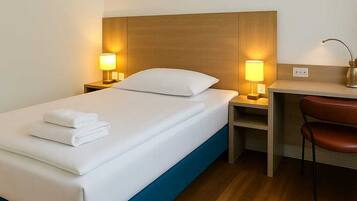 Ein Hotelzimmer mit einem Bett, zwei Nachttischlampen, einem Schreibtisch und einem Stuhl.
