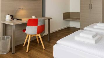 A hotel room with a bed, a desk, a chair, a television, and a wardrobe.