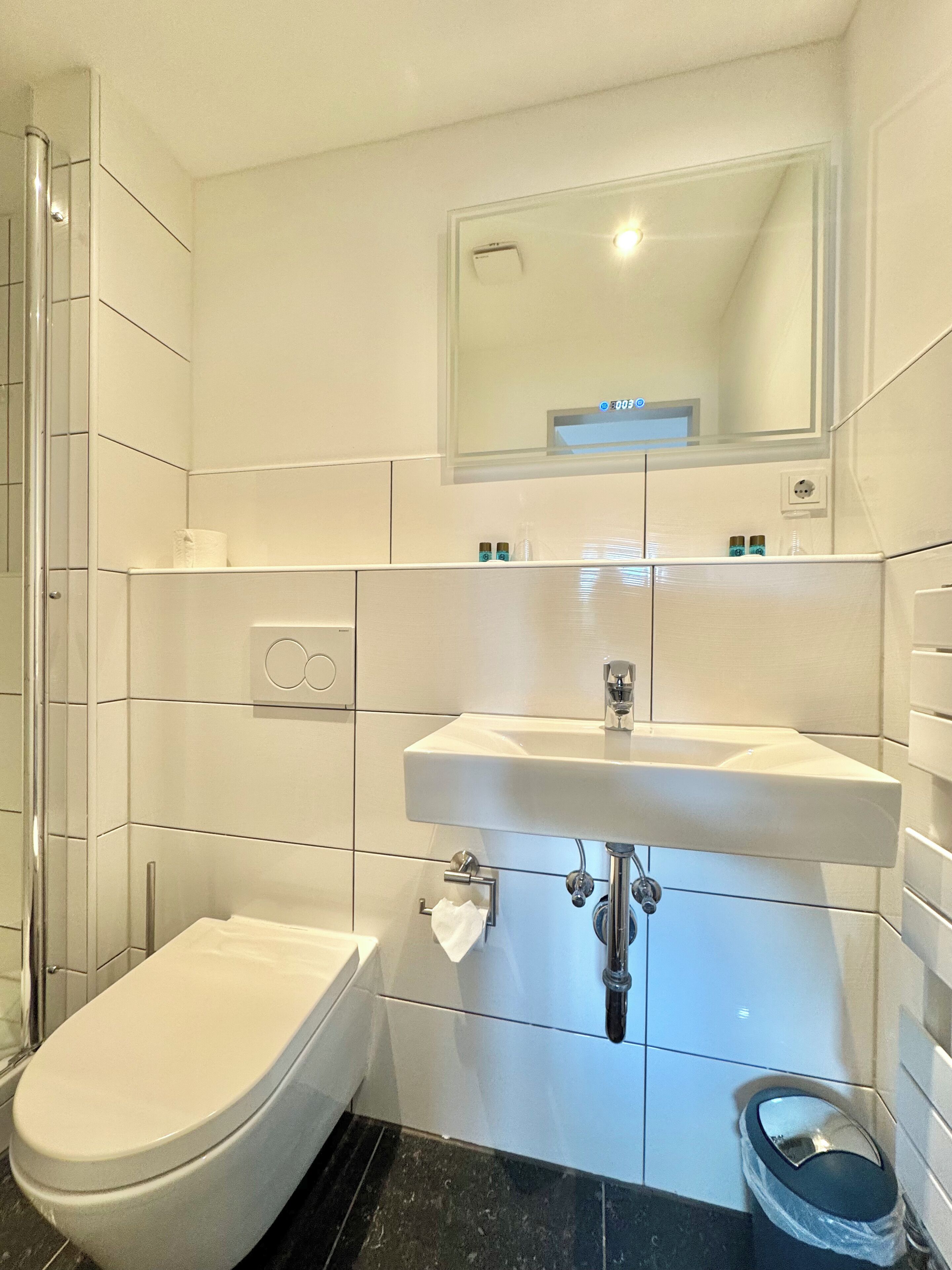 A modern bathroom with a white toilet, a sink, and a mirror above it.