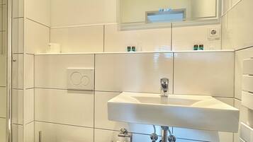 A modern bathroom with a white toilet, a sink, and a mirror above it.