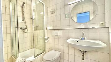 Ein modernes Badezimmer mit Duschkabine, Toilette und Waschbecken mit Spiegel darüber.