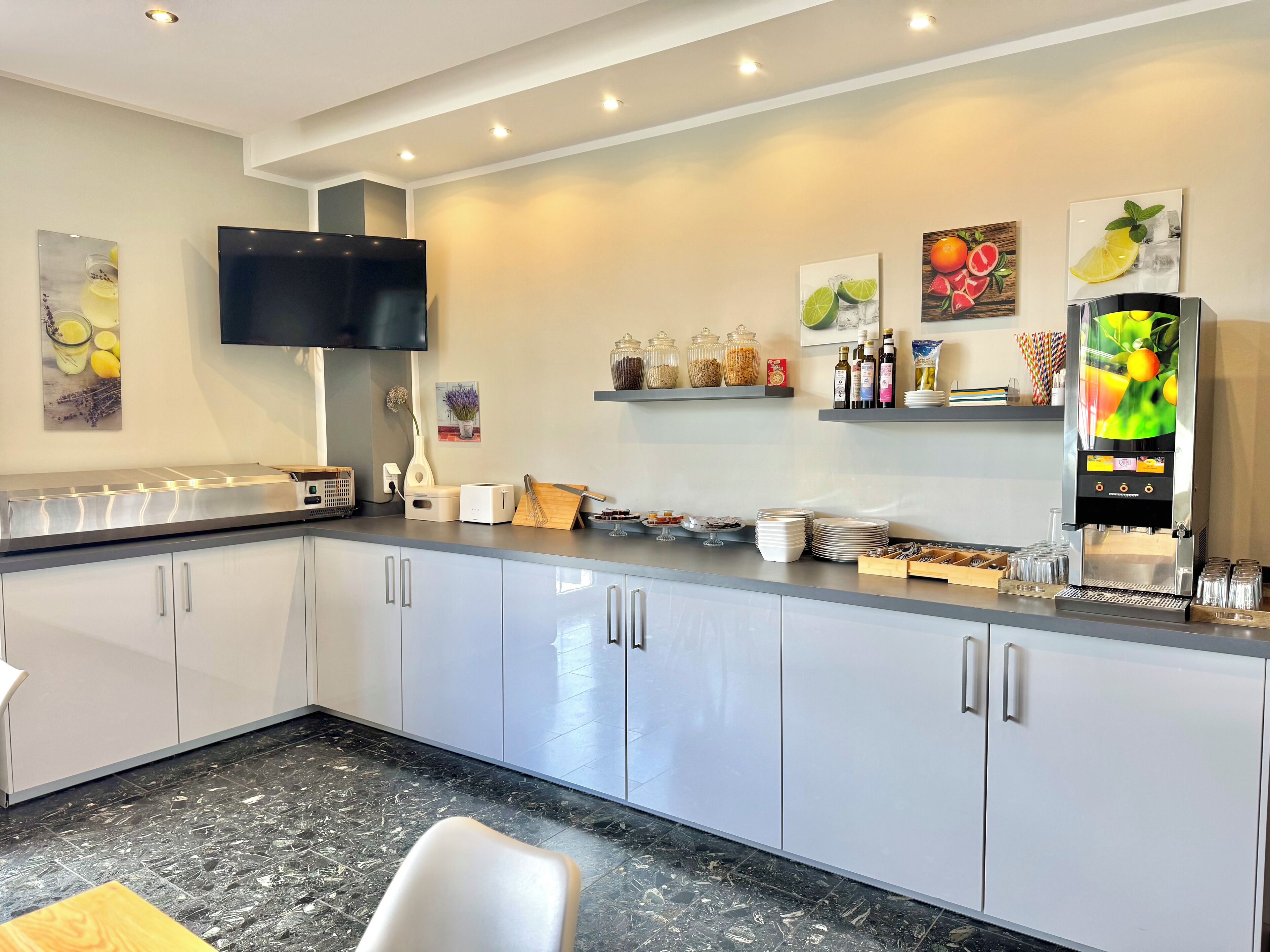Una cocina moderna con una televisión de pantalla plana, una cafetera y diferentes electrodomésticos.