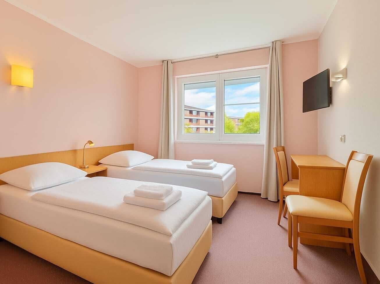 Ein Hotelzimmer mit zwei Betten, einem Schreibtisch und einem Stuhl.