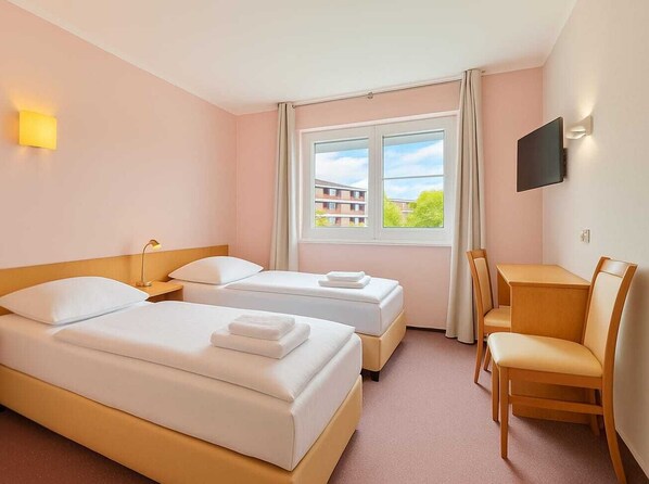 Une chambre d’hôtel avec deux lits, un bureau et une chaise.