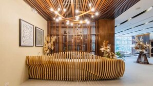 Una moderna zona de recepción con un banco de madera singular, obras de arte enmarcadas en la pared y una lámpara decorativa en el techo.