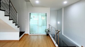 Ein modernes Interieur mit Holzboden, einer Treppe und einer Glastür zum Balkon.