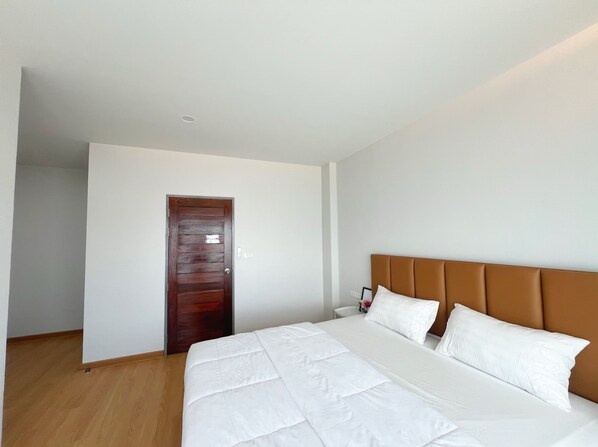 Une chambre d’hôtel avec un grand lit, une porte en bois et un mur blanc.