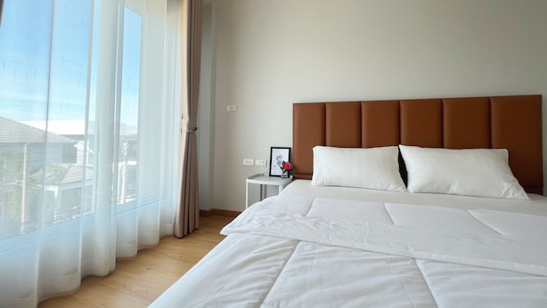 Ein Hotelzimmer mit einem großen Bett, einem Nachttisch, einem gerahmten Bild und durchsichtigen Vorhängen.