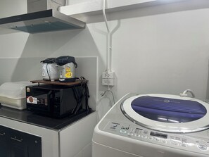 Une cuisine équipée d’un lave-linge, d’un cuiseur à riz et d’un four à micro-ondes.