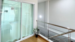Ein modernes Interieur mit Holzboden, einer Glastür mit satiniertem Glas und einem Metallgeländer.