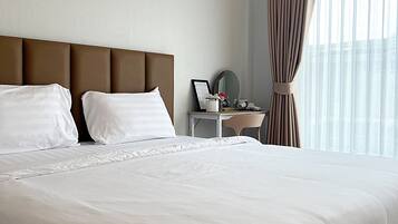 Een hotelkamer met een groot bed, een nachtkastje met lamp, een spiegel en een raam met gordijnen.