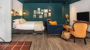 A modern bedroom with a bed, a sofa, a desk, and a television. - 4 Executive self catering Apartments, two with private hot tubs. (Cape Town)