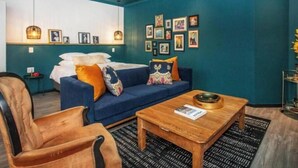 A modern living room with teal walls, a blue sofa, a wooden coffee table, and a leather armchair. - 4 Executive self catering Apartments, two with private hot tubs. (Cape Town)
