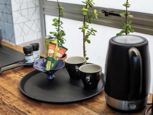 A kitchen counter with a coffee maker, two mugs, a small plant, and a canister. - 4 Executive self catering Apartments, two with private hot tubs. (Cape Town)