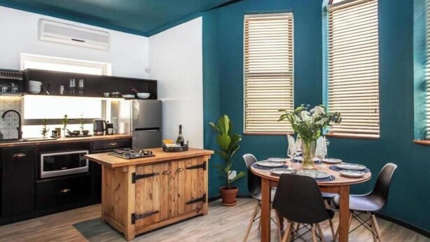 A compact kitchen with modern appliances, a wooden island, and a dining area with a table and chairs. - 4 Executive self catering Apartments, two with private hot tubs. (Cape Town)