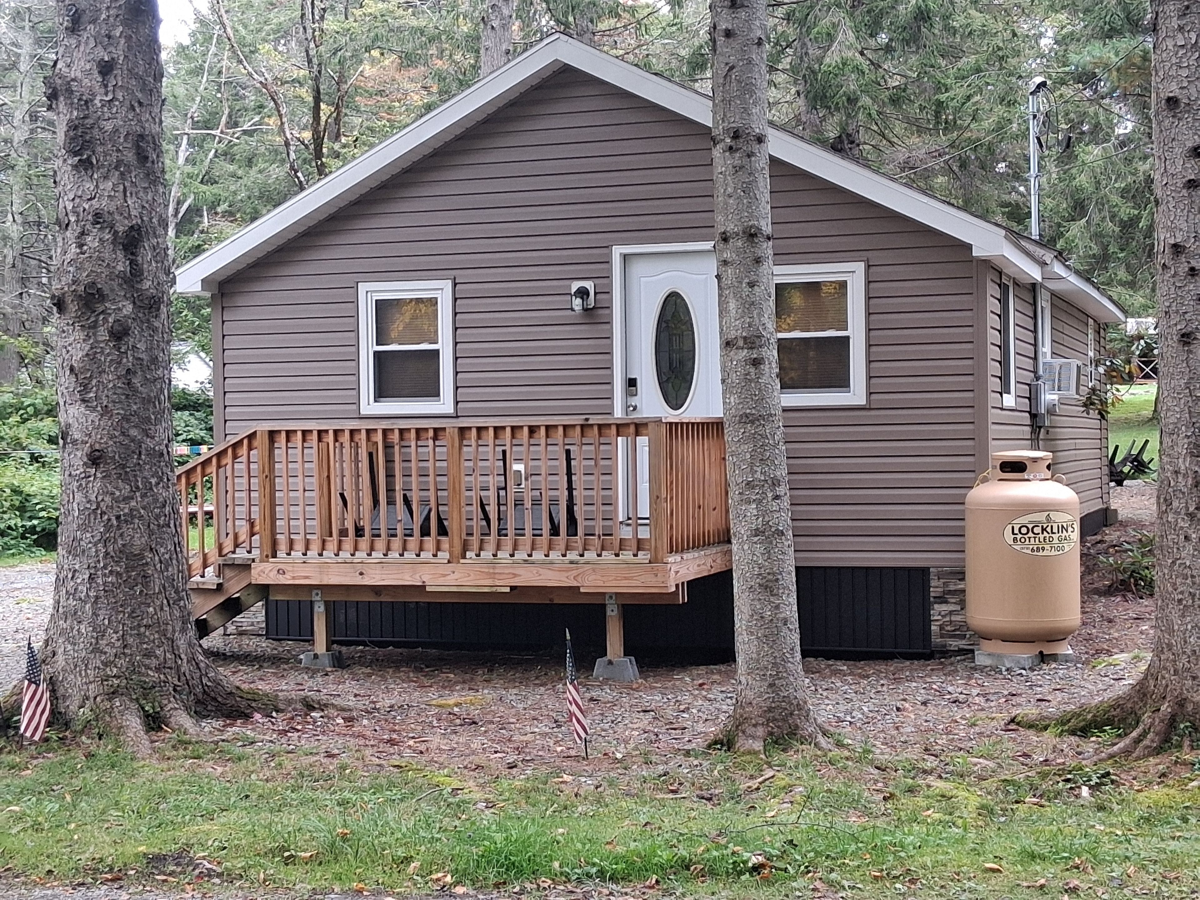 A small cabin with a wooden deck, two windows, and a door.