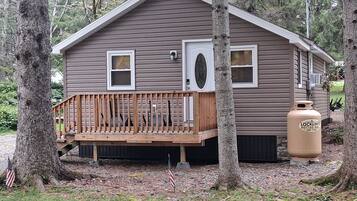 A small cabin with a wooden deck, two windows, and a door.