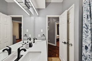 Un baño moderno con un lavamanos blanco alargado, grifería negra y un espejo.