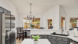 A modern kitchen with a large island, stainless steel appliances, and a view of the outdoors. - 2 minutes from lake, Pickleball, Hot Tub, Pool table! (Rowlett)