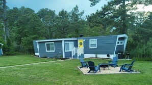 A mobile home with a porch, outdoor seating, and a small garden area.