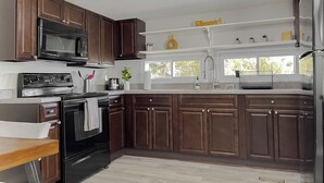 A modern kitchen with dark wooden cabinets, stainless steel appliances, and a granite countertop.
