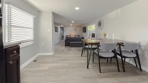 A modern kitchen with a dining area, featuring a wooden floor, white walls, and a built-in oven.