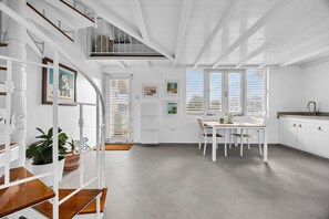 A bright, white interior with a dining area, staircase, and kitchen. - Beachfront With Pool Free Parking (Aguada)