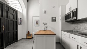 Une cuisine moderne avec des meubles blancs, un plan de travail en bois et un four à micro-ondes encastré.