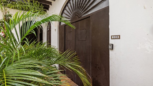 Un bâtiment traditionnel avec une porte en bois sombre et une petite enseigne indiquant le numéro 103.