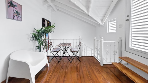 A room with a wooden floor, white walls, a ceiling fan, a table with chairs, a bench, and a potted plant. - Beachfront With Pool Free Parking (Aguada)