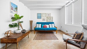 A living room with a blue sofa, a wooden coffee table, a grey armchair, and a large potted plant. - Beachfront With Pool Free Parking (Aguada)