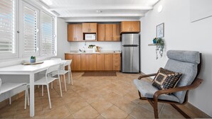 A compact kitchen with wooden cabinets, a stainless steel refrigerator, and a white dining table with chairs. - Beachfront With Pool Free Parking (Aguada)