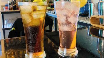 Zwei Gläser gekühlte Getränke mit Zitronenscheiben und Rosmarinzweig auf einer Bar.