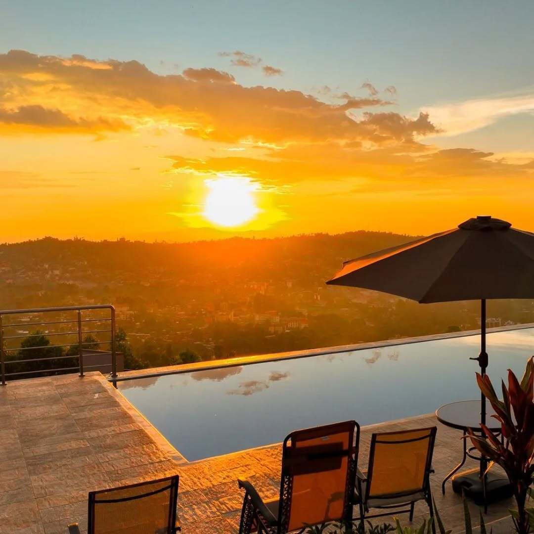 Una piscina en la azotea con vistas al atardecer, mobiliario exterior y un gran parasol.