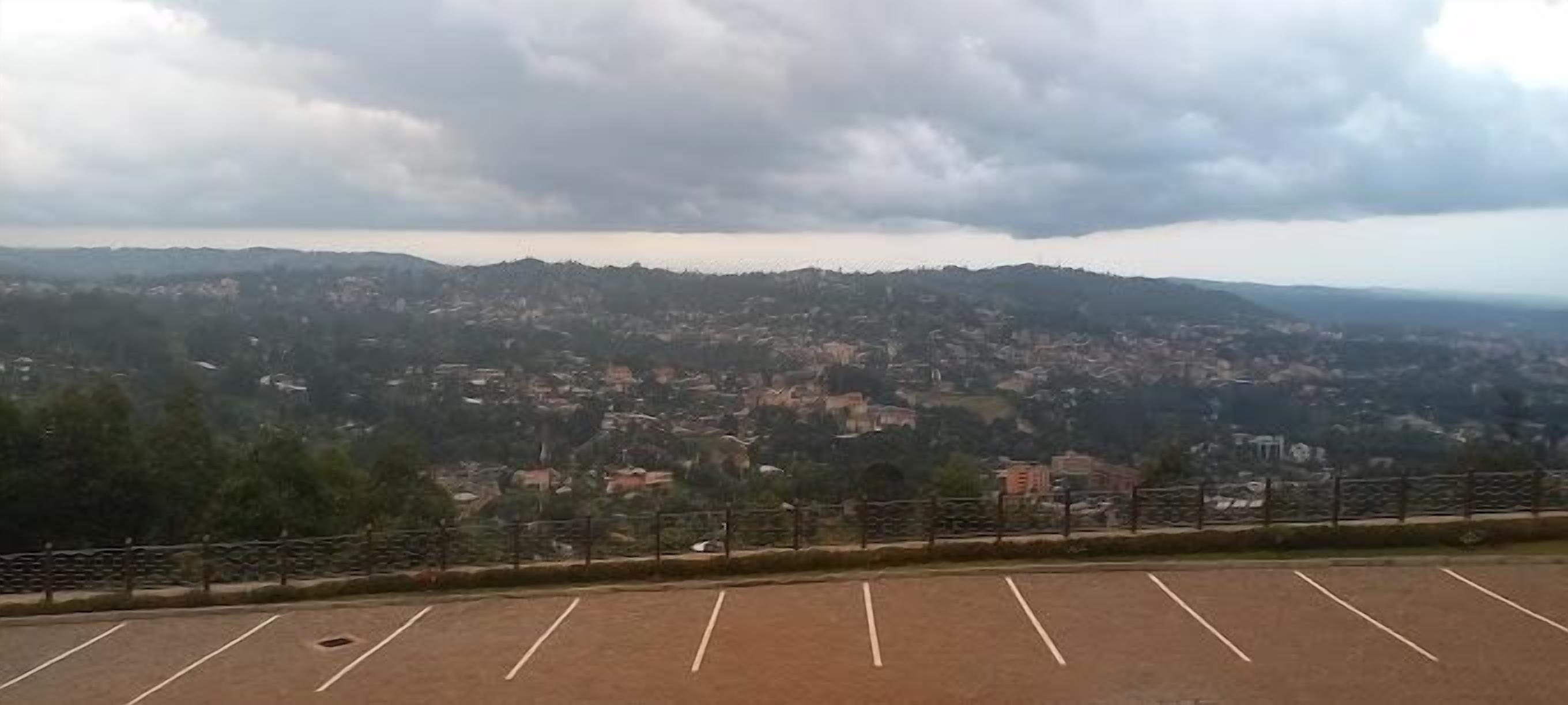 A parking lot with a view of a town and hills in the distance.