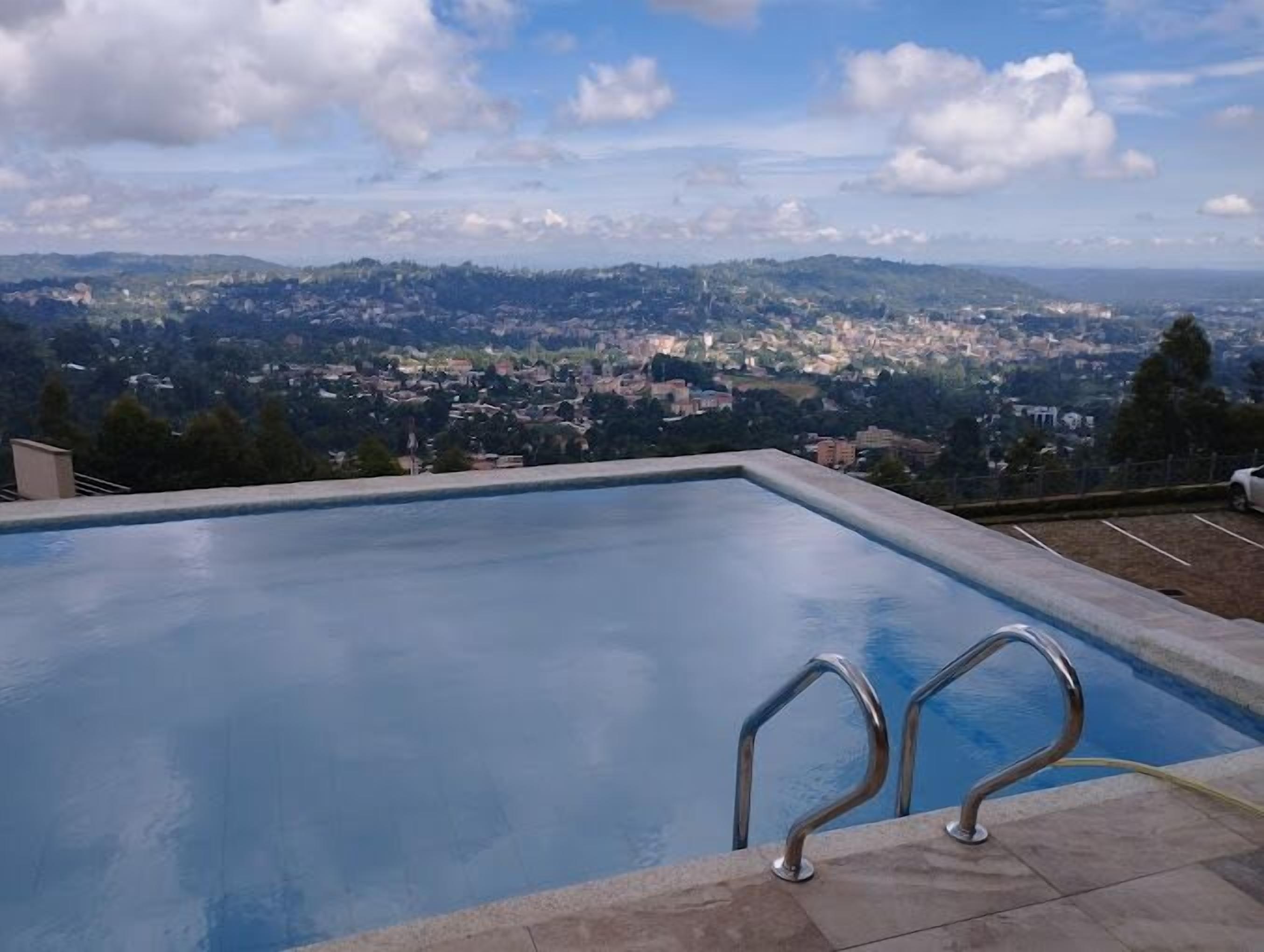 A swimming pool with a view of a cityscape and mountains in the background.