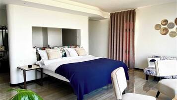 Una habitación de hotel moderna con una cama grande, un escritorio, una silla y una planta verde considerable.
