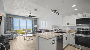 Una cocina moderna con una isla grande, armarios blancos y electrodomésticos de acero inoxidable.