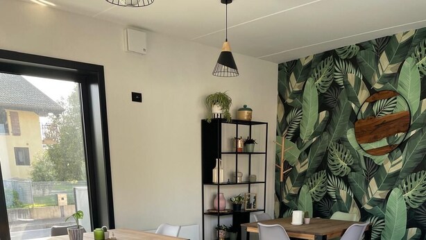Un espace repas moderne avec une table en bois dressée pour le petit-déjeuner, entourée de chaises grises.