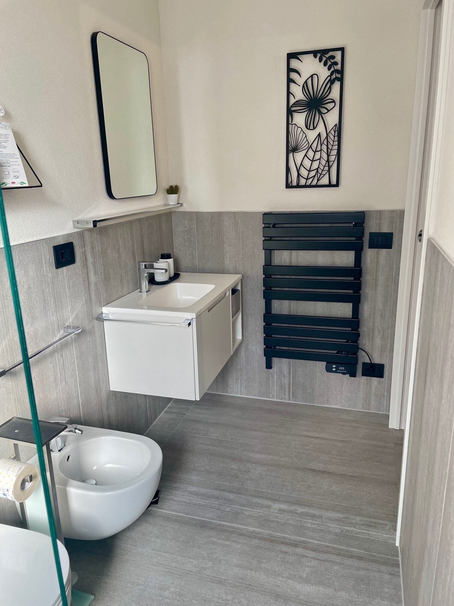 A modern bathroom with a white sink, a freestanding toilet, and a wall-mounted towel rack.