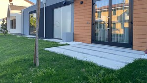 Une maison moderne à deux étages, dotée d’une grande porte-fenêtre coulissante, d’un garage et d’une pelouse bien entretenue.