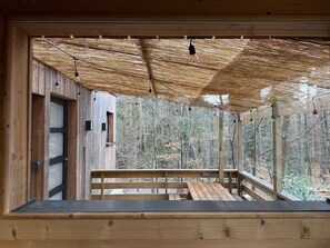 A wooden cabin with a thatched roof, a wooden deck, and a view of a forest. - Under the pines with sauna and jacuzzi (Emilie) (Labaroche)
