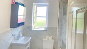 A bathroom with a sink, mirror, toilet, and shower.