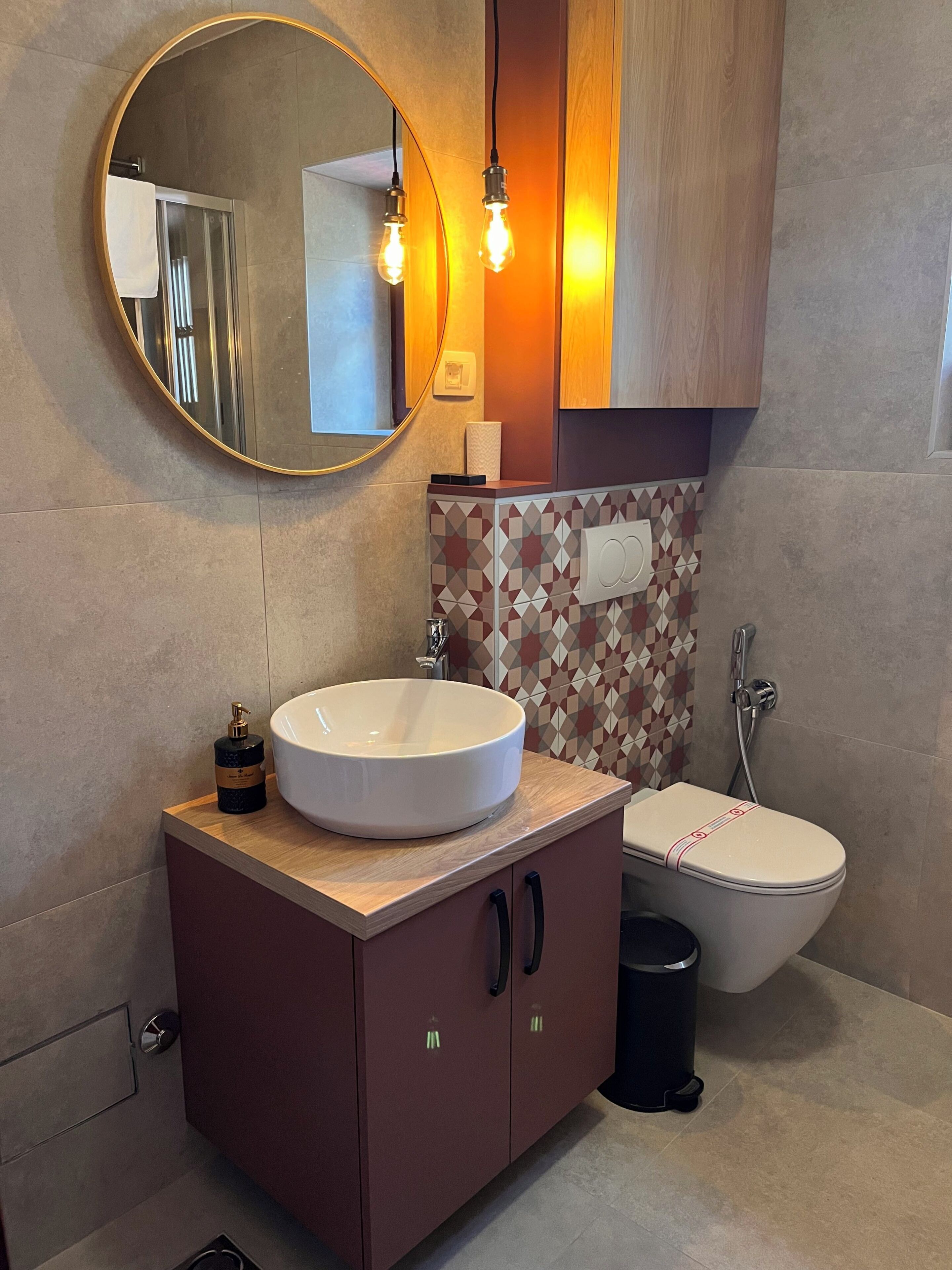 Un baño moderno con un espejo redondo, un lavabo blanco, un inodoro y una ducha.