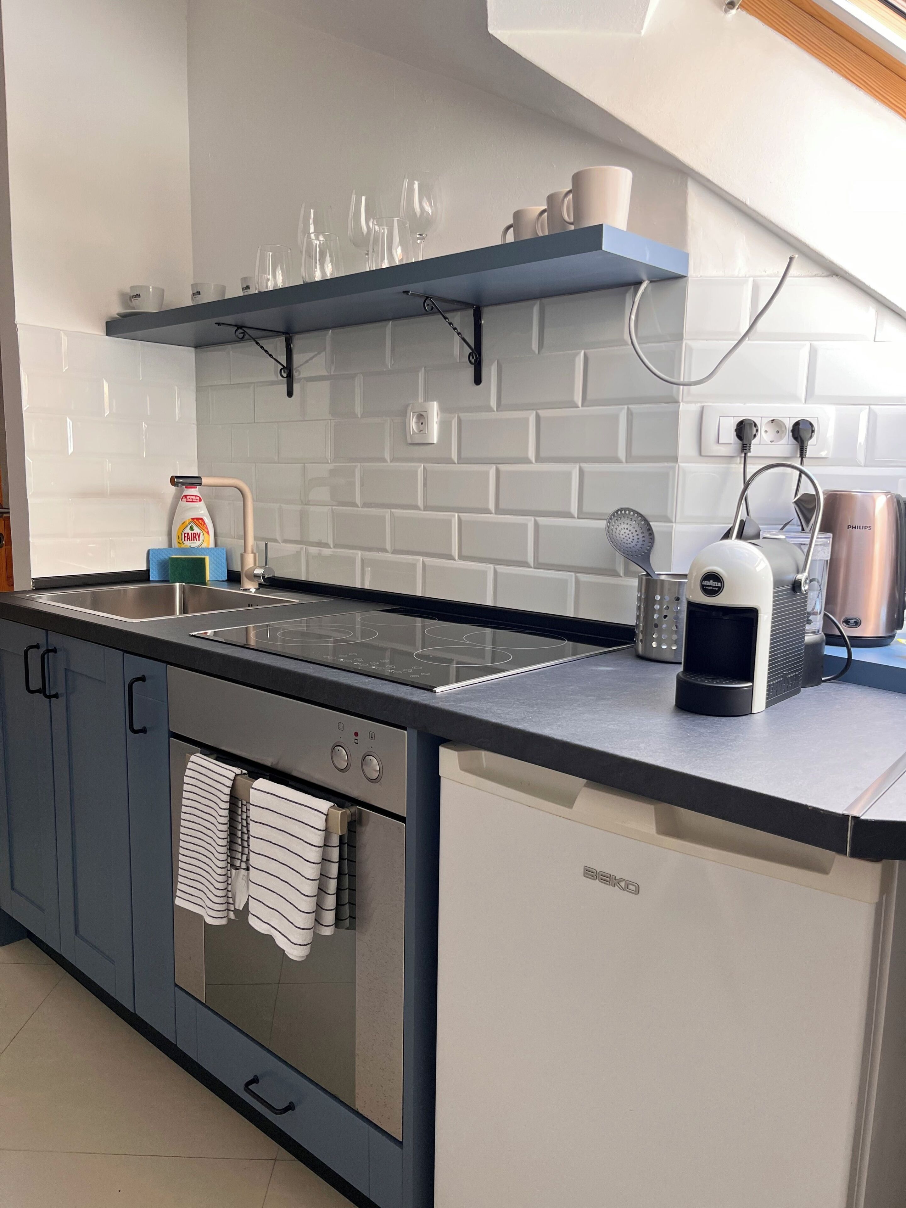 A modern kitchen with a built-in oven, a coffee maker, and a dish rack.