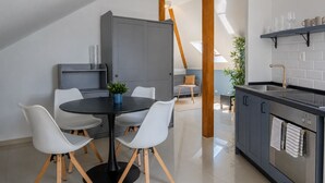 A modern kitchen with a dining area, including a round table with chairs, a grey cabinet, and a built-in stove. - Old Town Church Bells (Kotor)