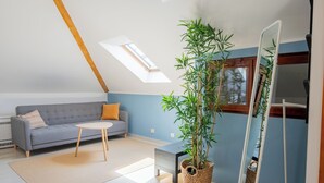 A modern living room with a grey sofa, round coffee table, and a large potted plant. - Old Town Church Bells (Kotor)