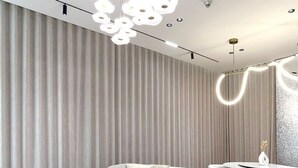 Ein modernes Wohnzimmer mit einer gebogenen Eckcouch, einem runden Couchtisch und einem großen, strukturierten Teppich.